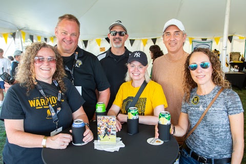 Alumni wearing black and gold gathering in the VIP Tent with drinks