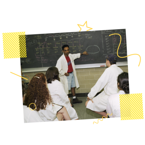 Man explaining on blackboard to others in a lab in 1998
