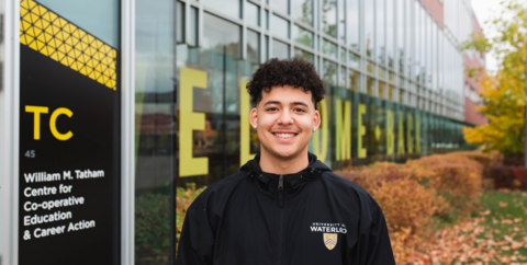 male student smiling at camera beside tatham center building