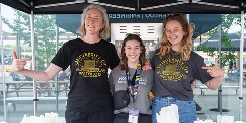 Volunteers smiling and pointing towards their University of Waterloo shirts