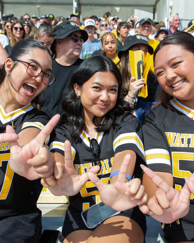 students holding up a w sign