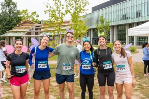 A group of runners pose on campus wearing athletic gear and fairy wings