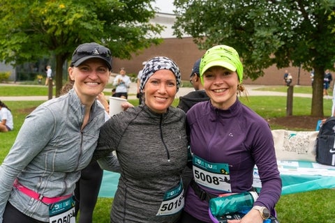 Three runners pose in their gear on campus