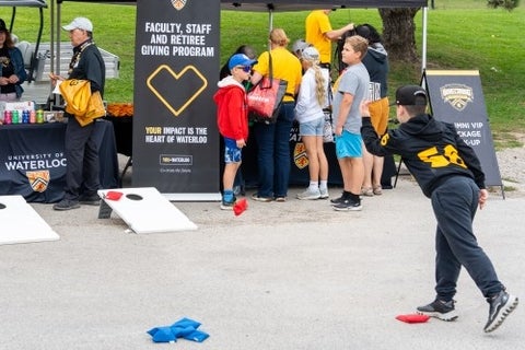 Young attendee throws a bean bag in a parking lot party game