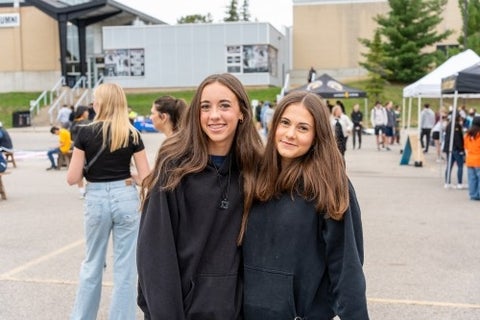Young attendees smile together at the parking lot party