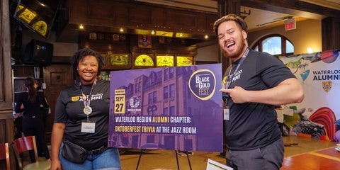 UWaterloo volunteers smiling around an event sign