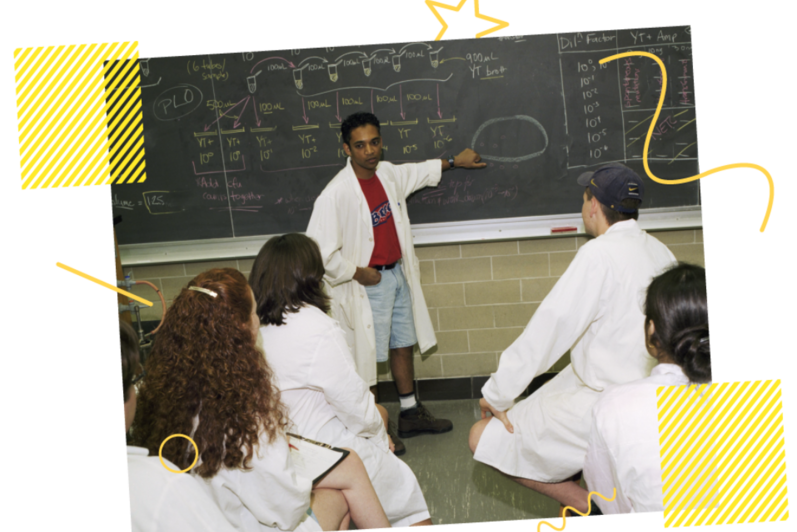 Man explaining on blackboard to others in a lab in 1998