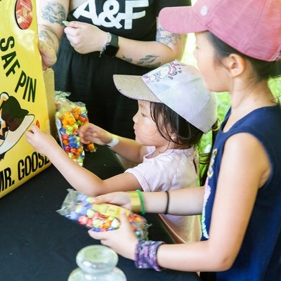 Children playing pin the safe pin on the goose at a booth