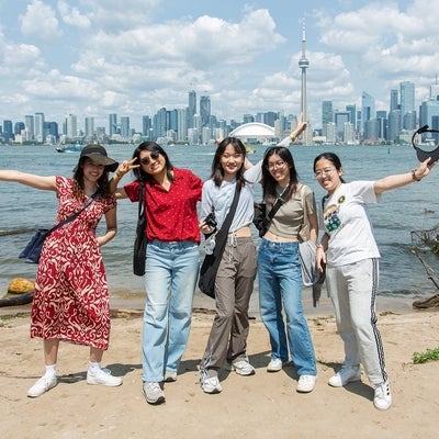 Five people posing for a group photo in front of the Toronto skyline