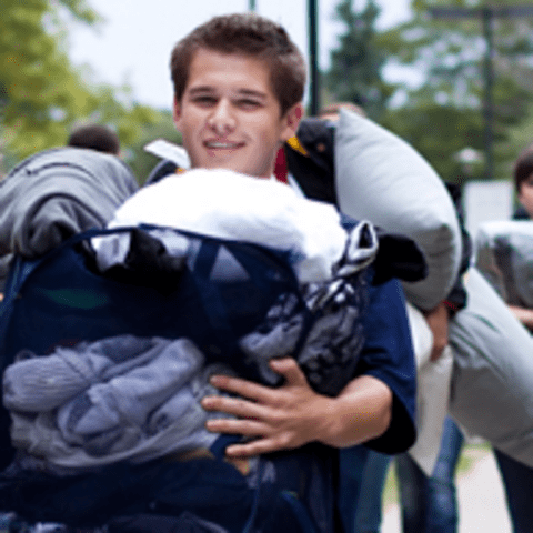 Young man carrying bag of laundry into student residence
