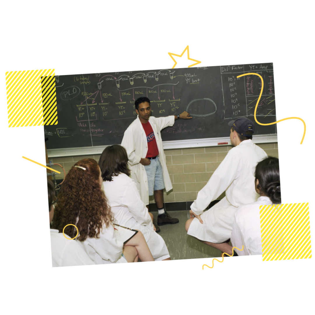 Man explaining on blackboard to others in a lab in 1998