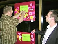 Two men putting notes on a bulletin board
