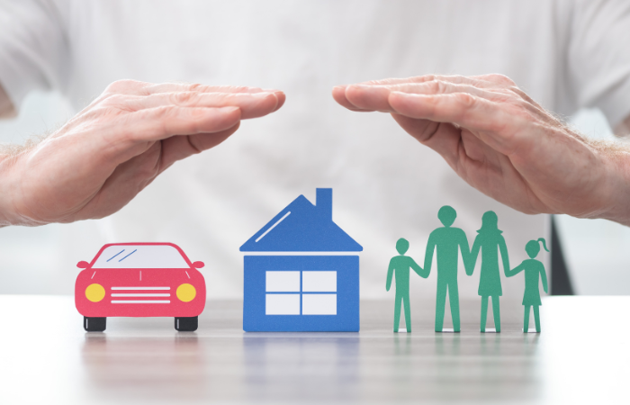 hands above a car, house and family representing car insurance, home insurance and life insurance