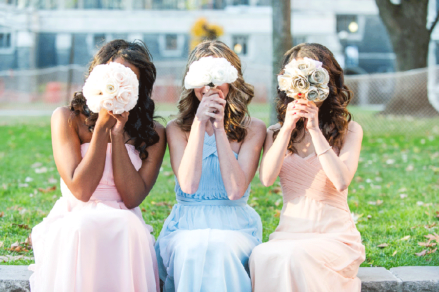 Three bridesmaids holding flowers over there faces