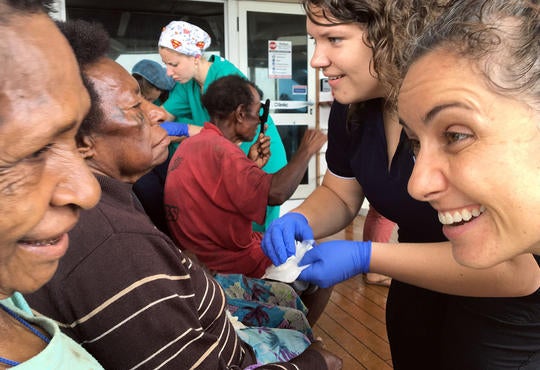 Alumnus Jen Kurylowicz greets woman at remote health clinic.