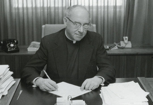 Father Cornelius Siegfried at desk in 1974.