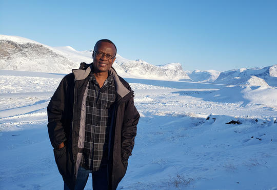 Wilfred Ntiamoah stands in front of snowy tundra.