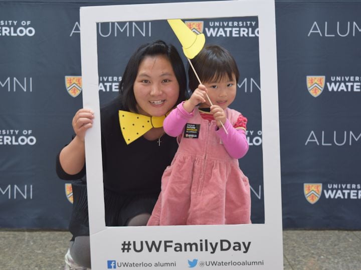 Mother and young daughter pose in alumni picture frame at Family Day.
