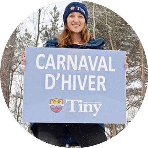 Maggie Off holds Carnaval D'Hiver sign for Tiny's winter festival.
