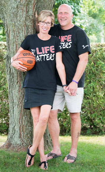 Doug and Sandra Ranton holding hands and holding son Jacob's basketball.