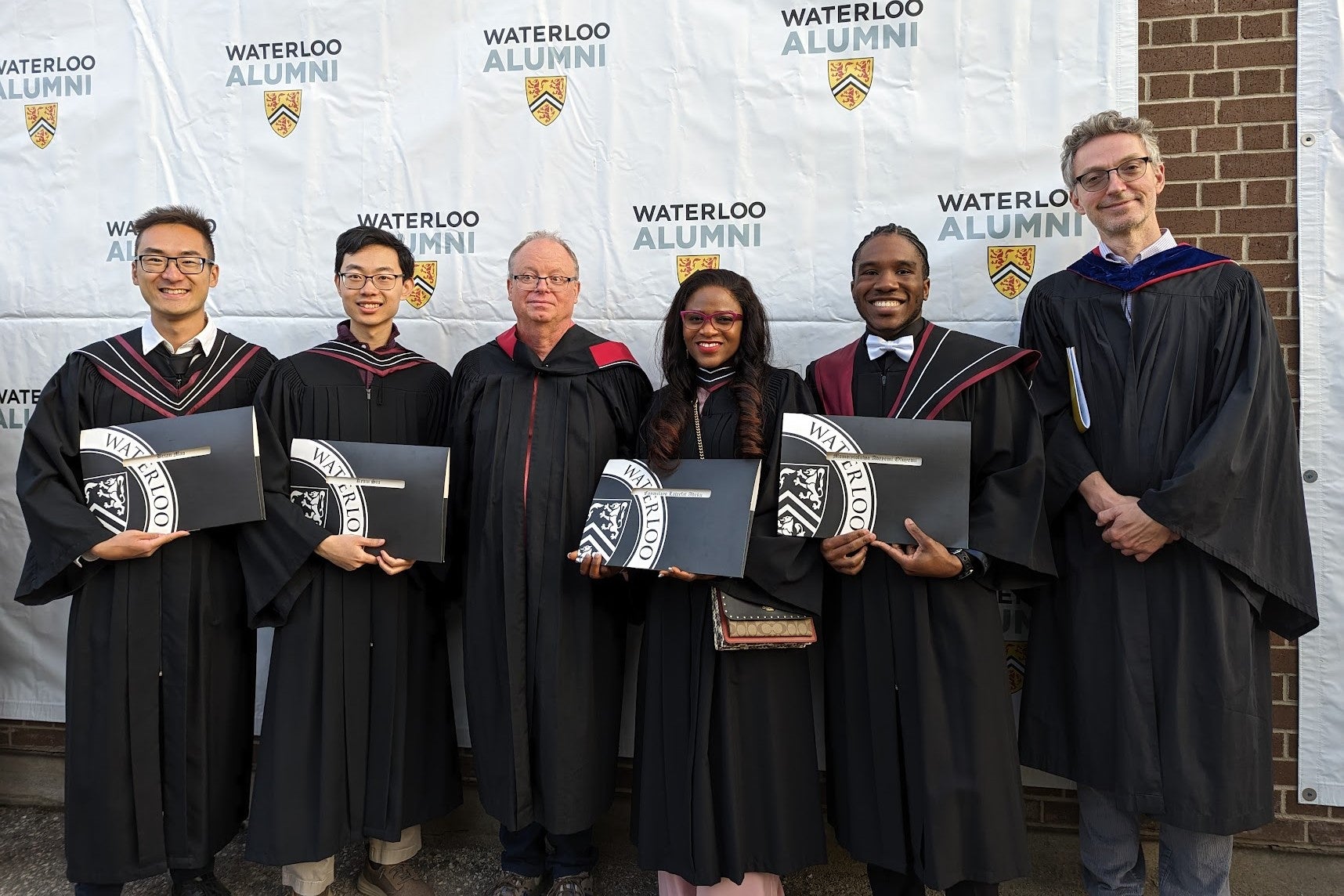 graduate students holding diplomas at convocation