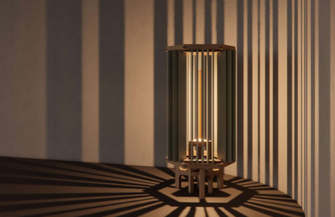 a slatted wooden lamp casts a dramatic shadow against a table and wall