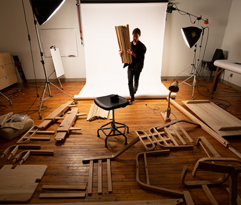 a student stands in front of a white photography backdrop in the centre of the school of architecture photo studio