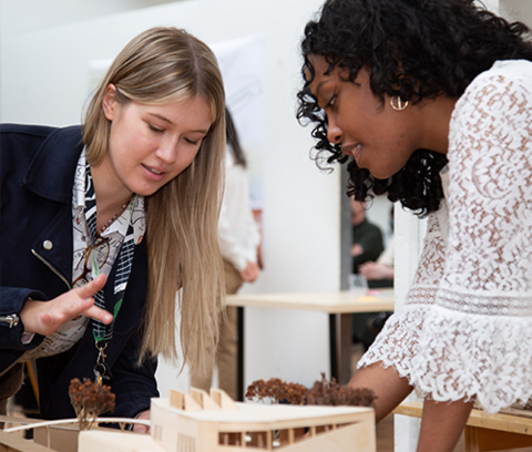 two students discuss an architectural model