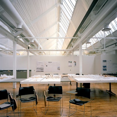 A room that has serveral tables and chairs displaying wood model of buildings