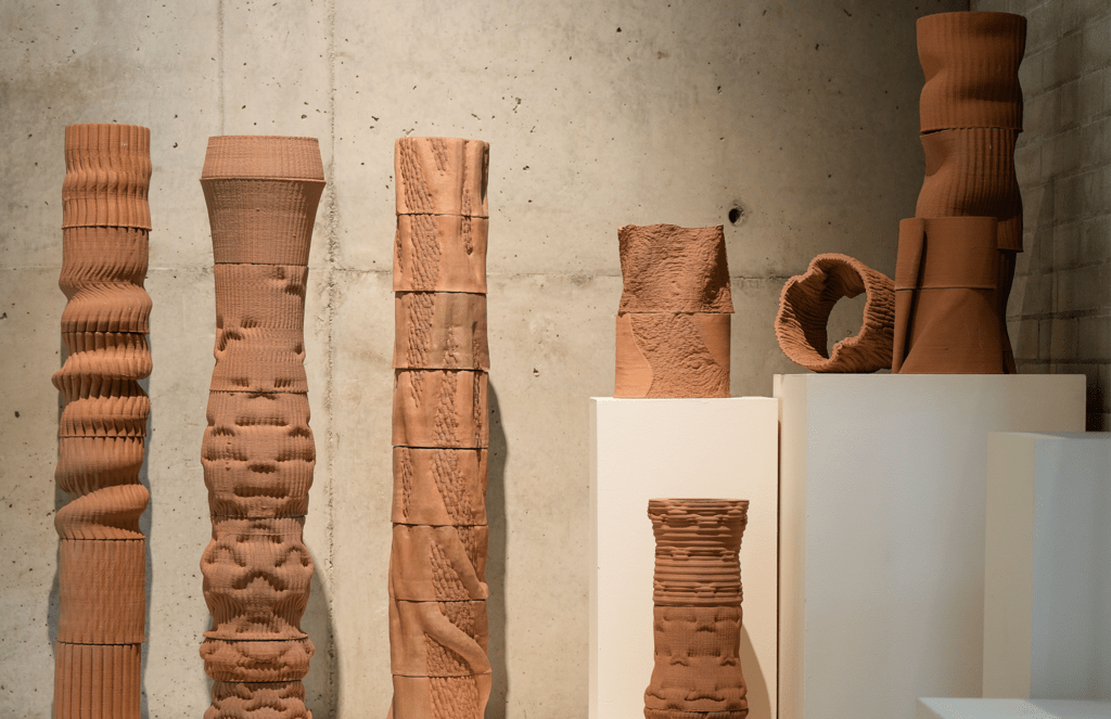 seven clay sculptures on display in a gallery