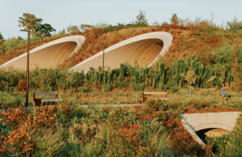 a field in the fall with a large dome structure built into the landscape