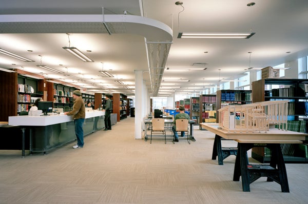 Two students are talking with librarians at the front desk