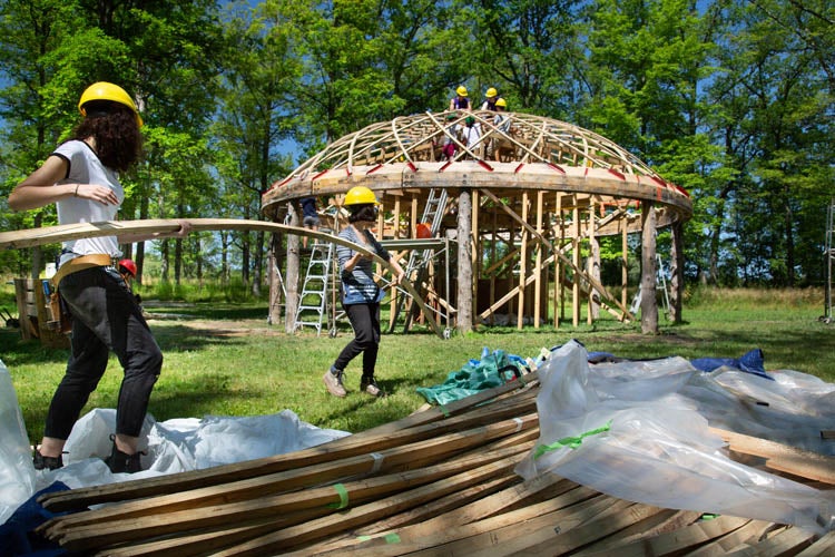 students taking pre-bent wood to arbour structure