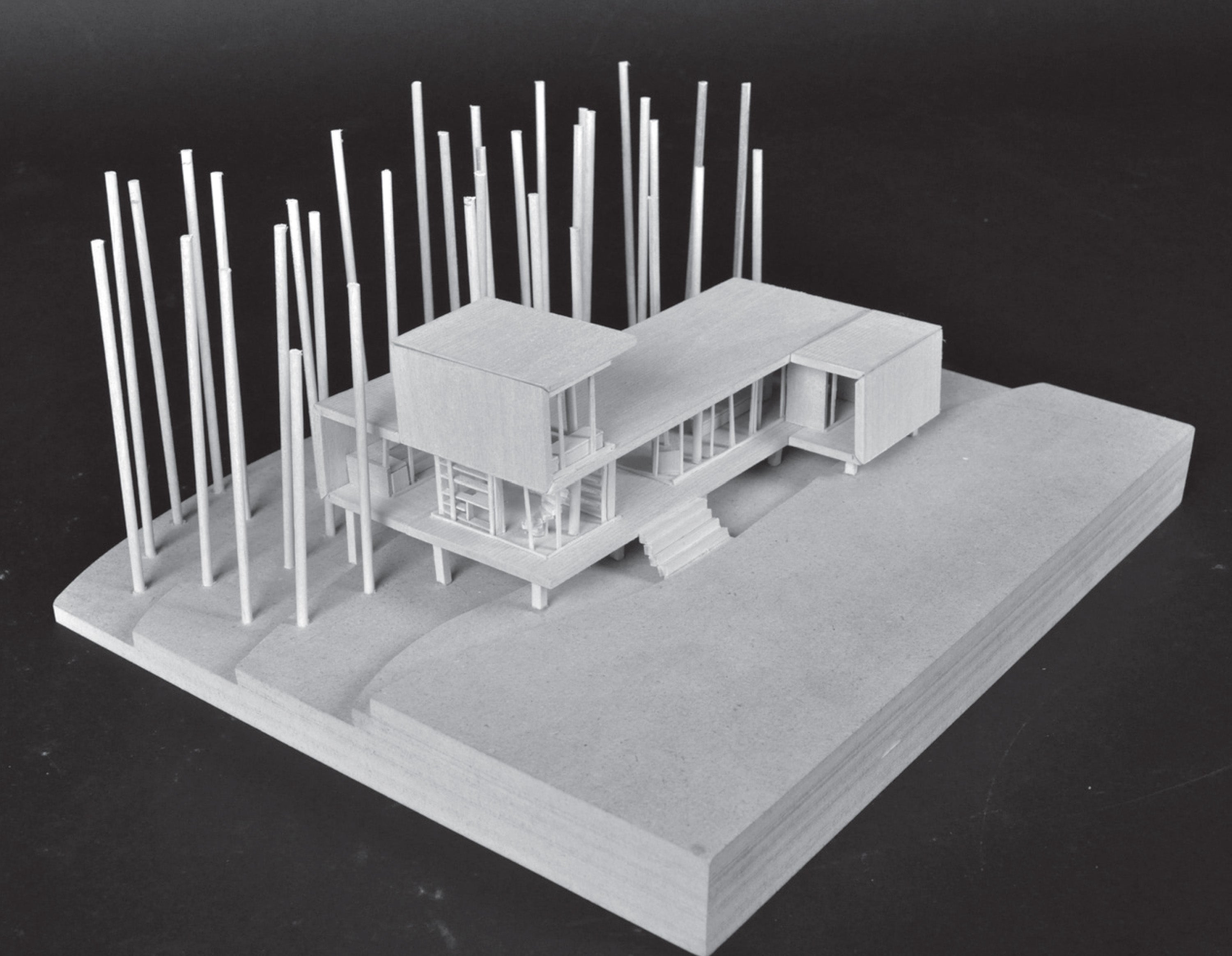 A wooden physical model of the house design. The house is on a sloped hill, with a number of trees surrounding the backyard.