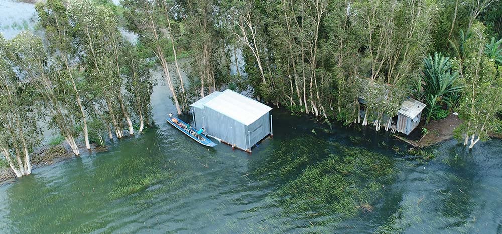 retrofitted home on flooded land, man in boat