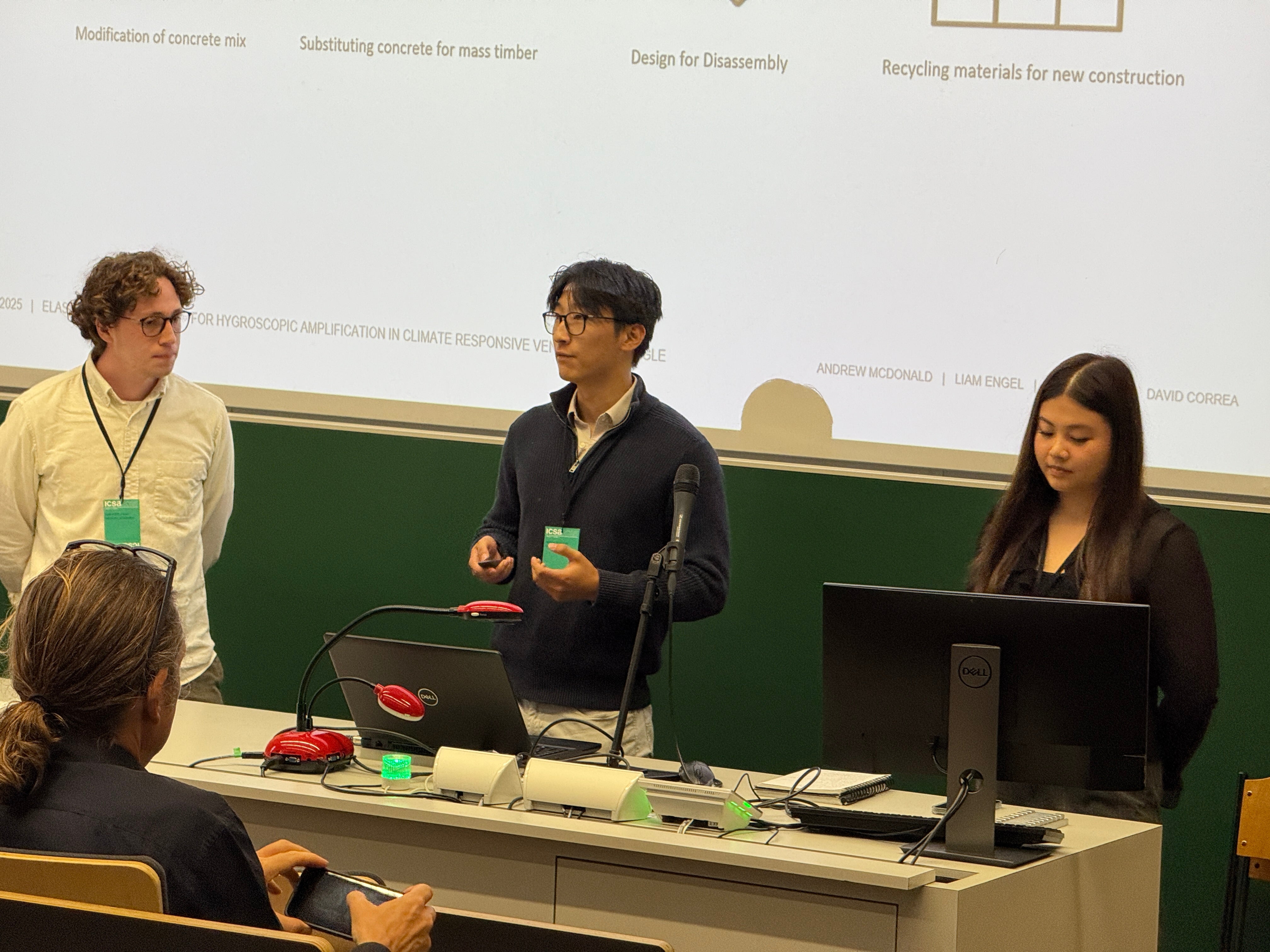 three students present research in a small lecture hall