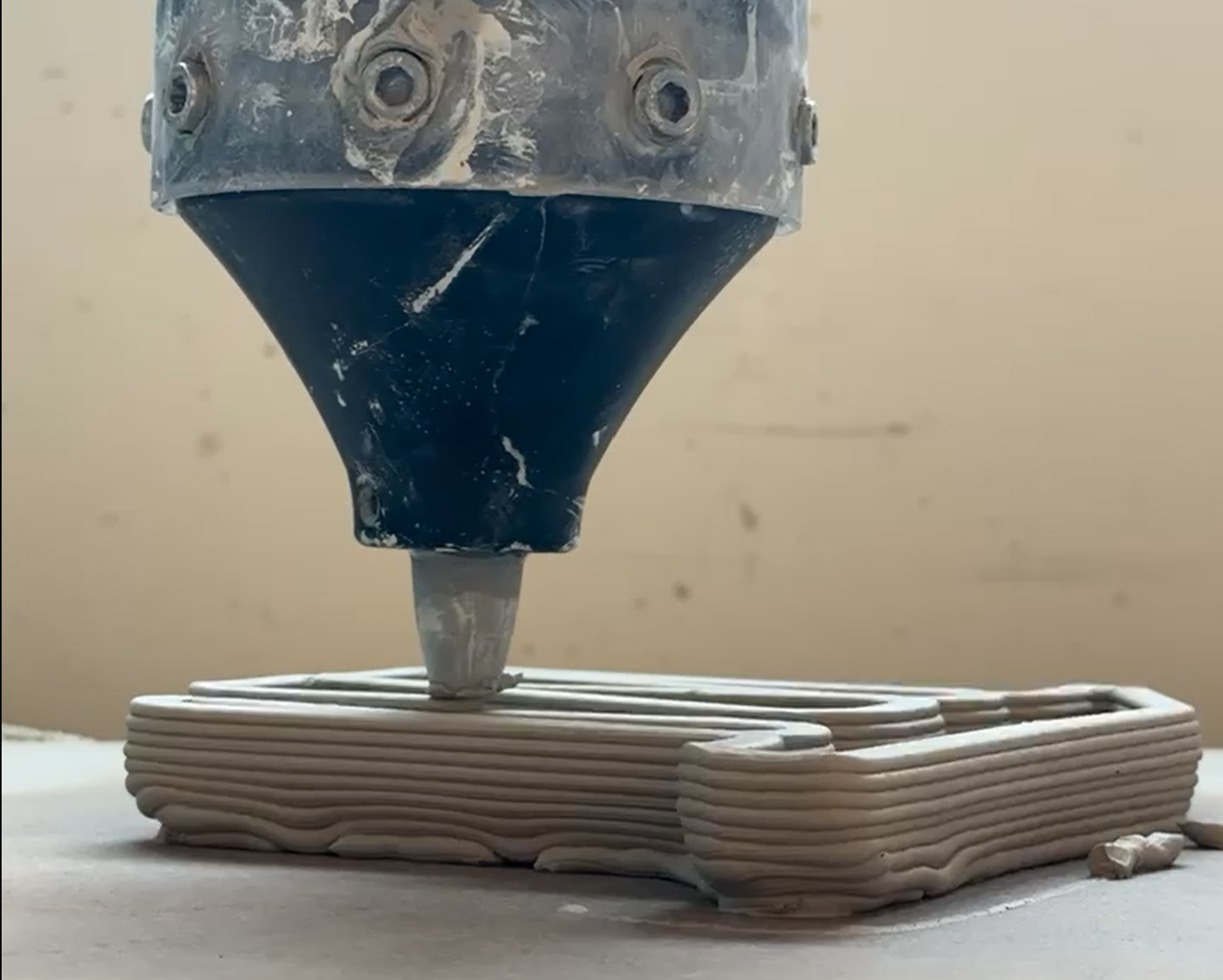 closeup of a 3d printer printing a clay structure
