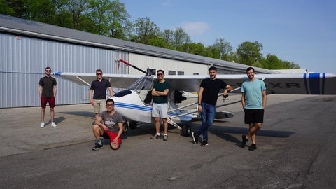 A plane with 6 people standing in front of it