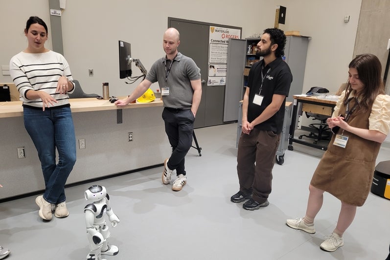 NTNU delegates and Waterloo hosts gather around a NAO robot demonstration at RoboHub, May 2026.
