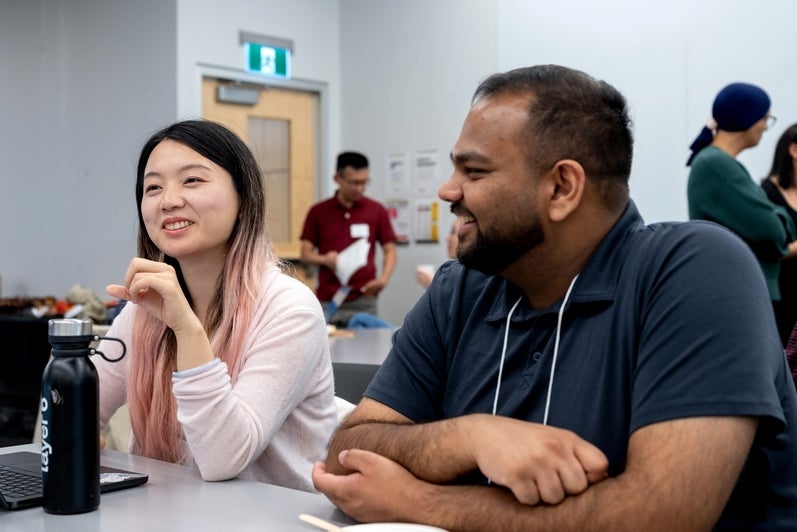 Two attendees smile while chatting at a table during the TD Layer 6 visit