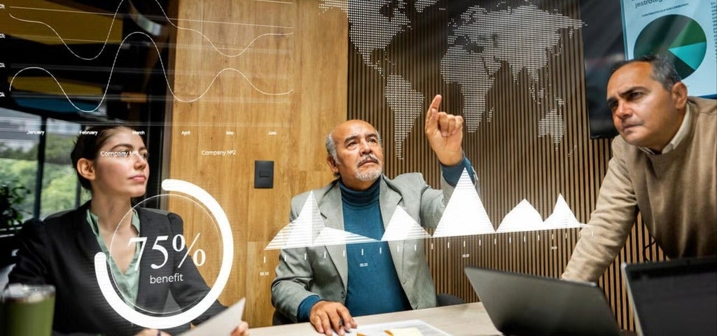 Business professionals analyze projected data visualizations during a meeting, with charts, graphs, and a world map overlay illustrating global analytics and decision-making.