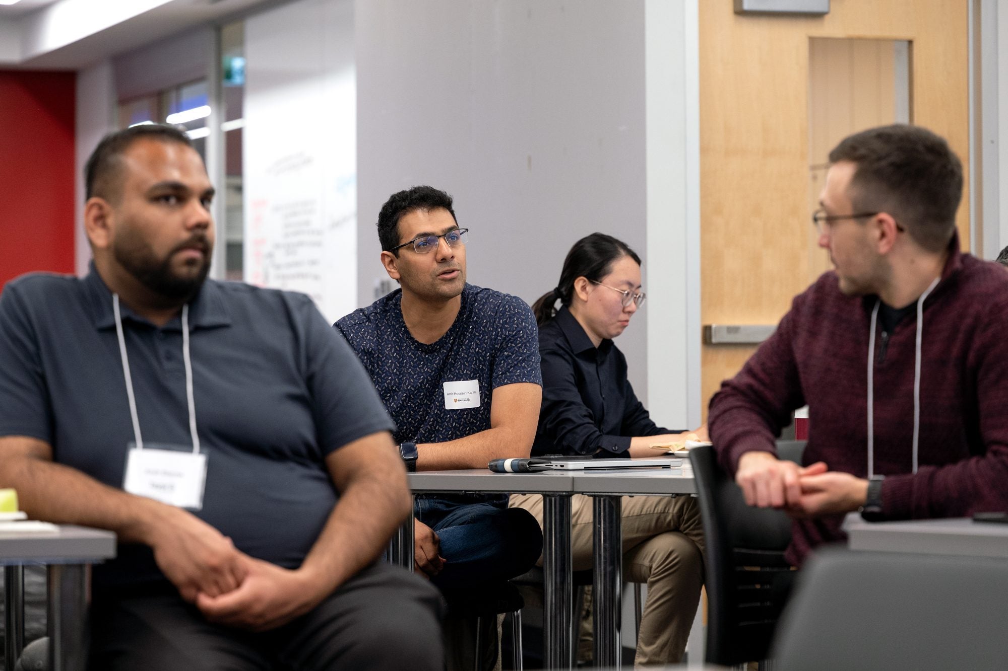 Attendees seated around tables listen to a presentation
