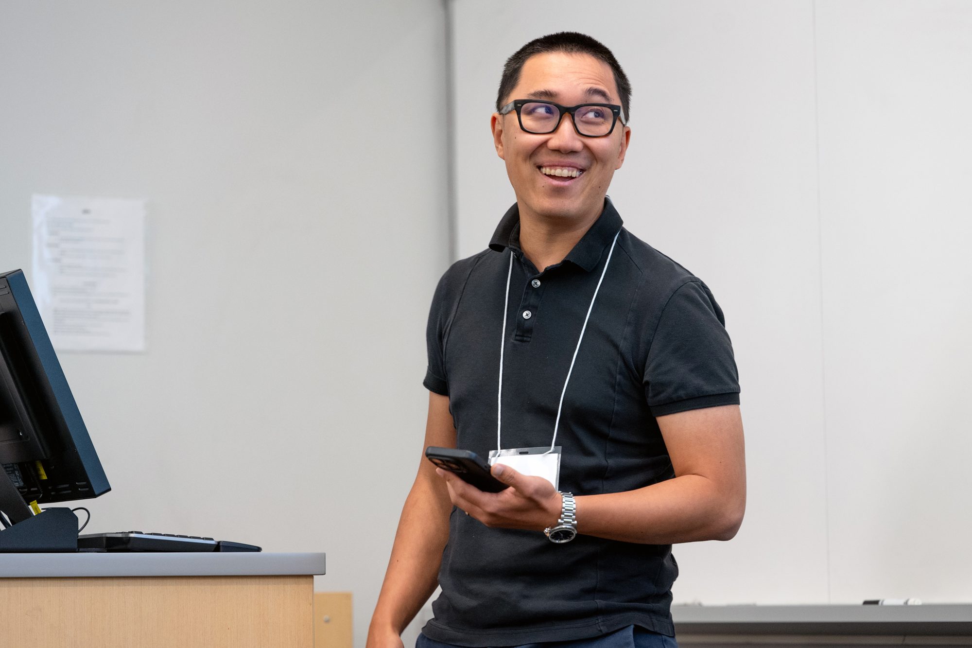 A speaker smiles while presenting at the front of the room