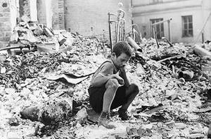 Archival photo of a boy sitting alone in a destroyed part of Warshaw circa 1939