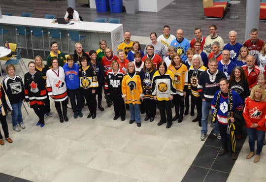 group of faculty and staff gather in hockey jerseys
