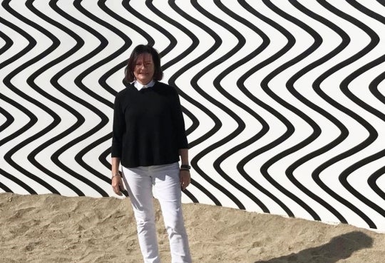 Lenora Hume standing in sand in front of large public artwork