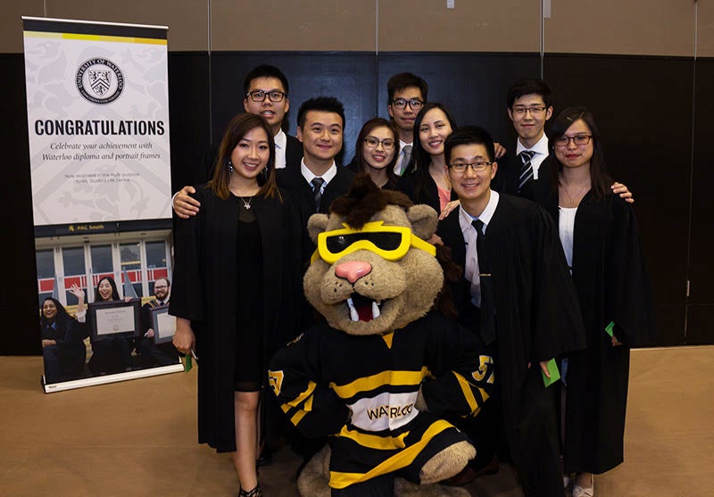 Arts graduates pose with the King Warrior lion mascot