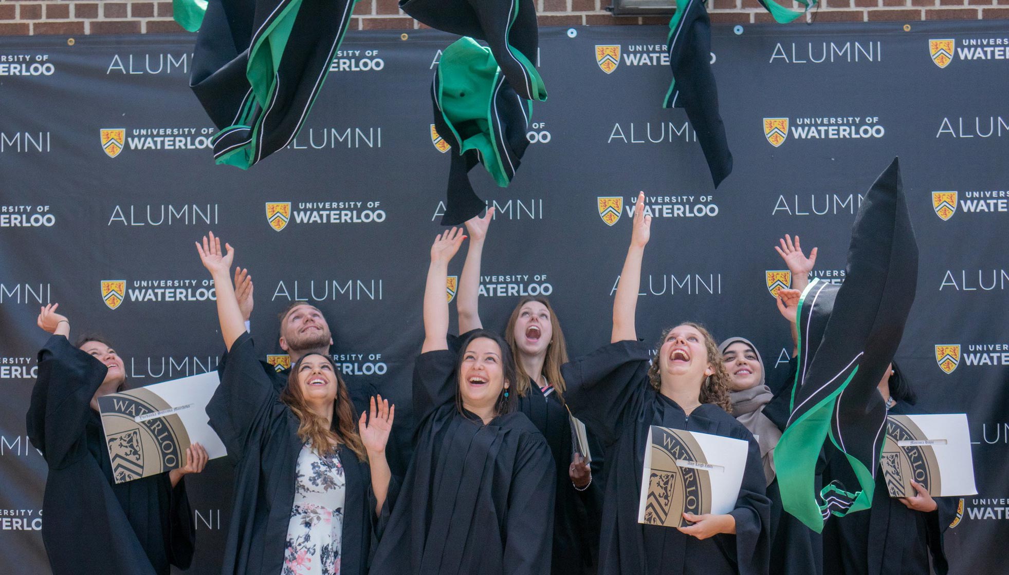 Group of arts graduates throwing their academic hoods in the air