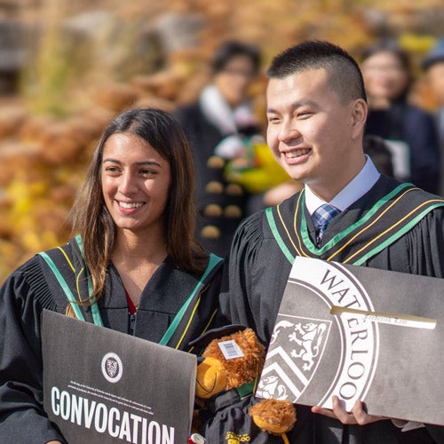 A woman and man show off their diplomas