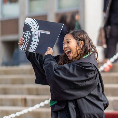 Women excitedly holds up her diploma